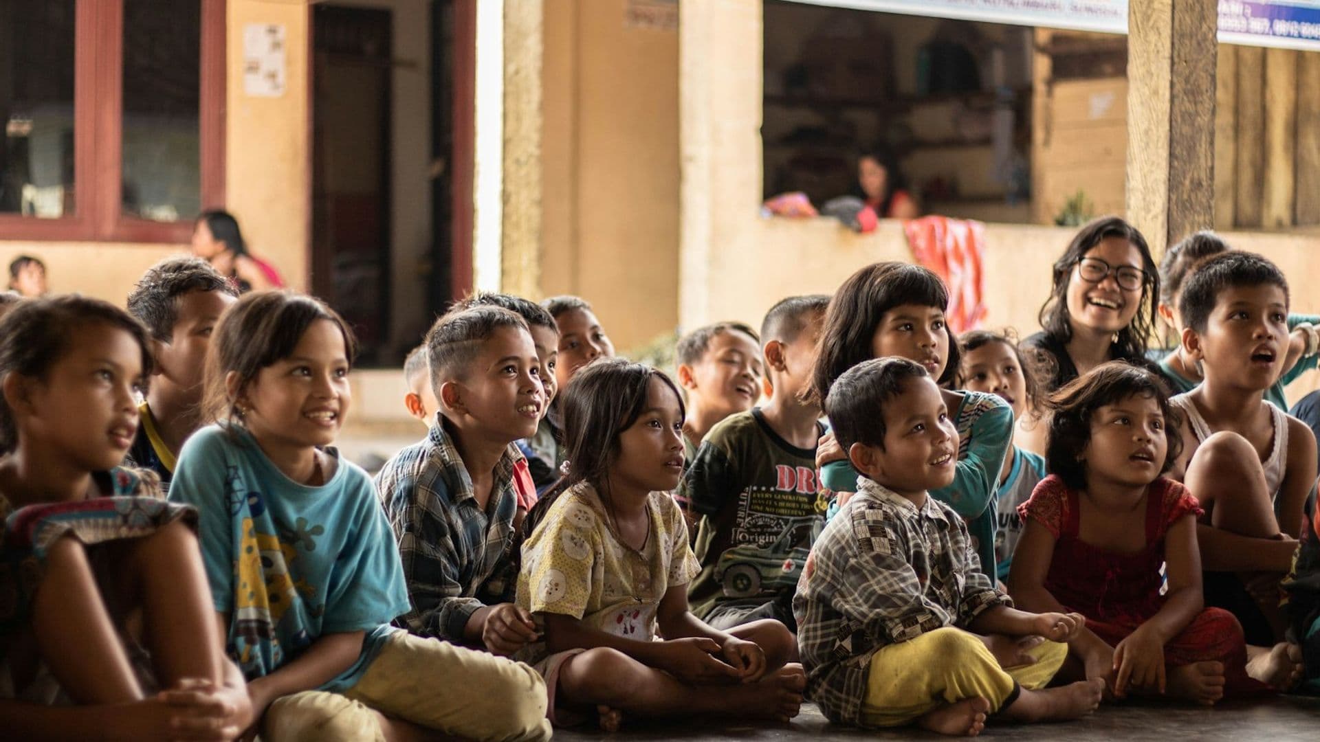 Children gathered together, engaged and smiling, in a community learning setting
